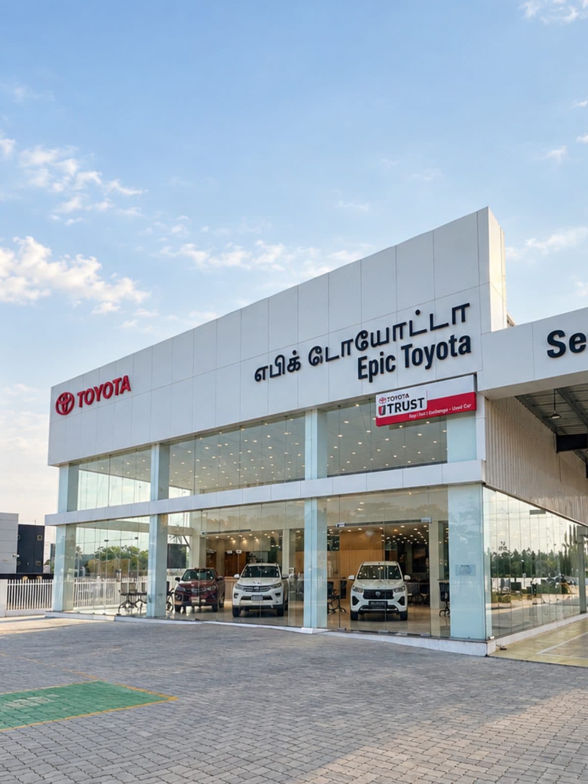 The completed Epic Toyota dealership seen from the forecourt in daylight, its glazed showroom open to the street.