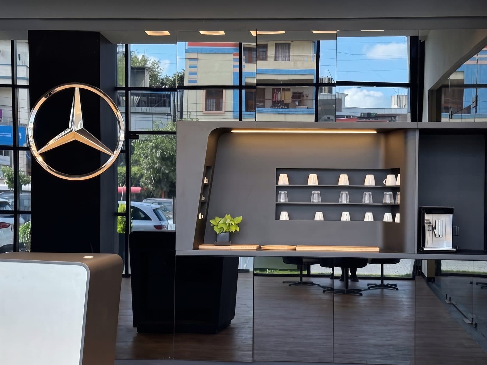 The illuminated Mercedes star beside a hospitality counter, its shelves lined with cups and glasses, in the Silver Star showroom.