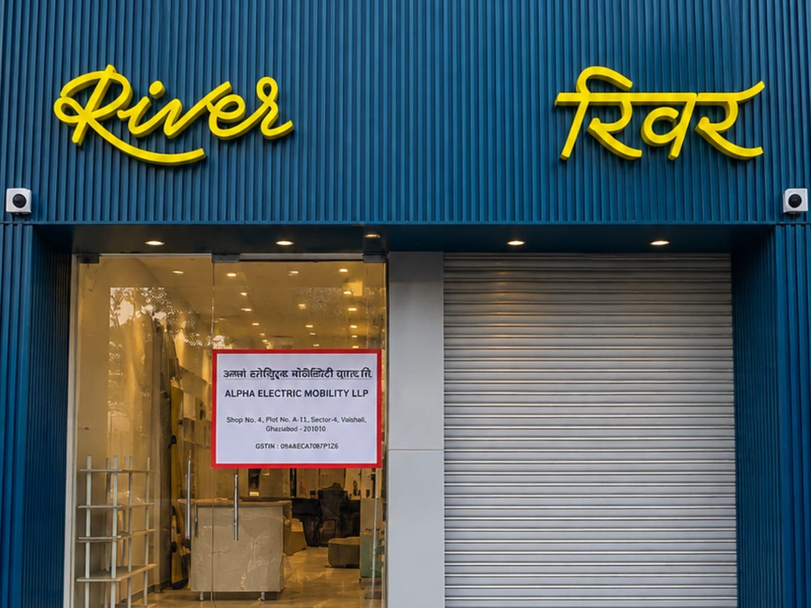 The River storefront, its name in yellow script on a deep blue corrugated facade above a glazed entrance.